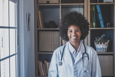 Portrait of female doctor standing by window