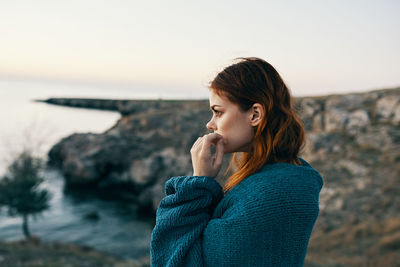 Young woman standing at beach against sky