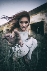 Portrait of young woman with arms raised on field