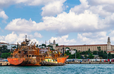 Boats moored at harbor against sky