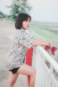 Side view of woman standing against railing