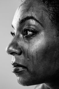 Close-up of woman crying against gray background
