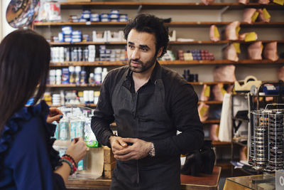 Rear view of female customer talking with man at shoe repair store