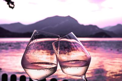 Close-up of drinking water in lake against sunset sky