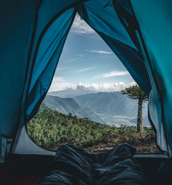 Low section of person relaxing in tent against mountains