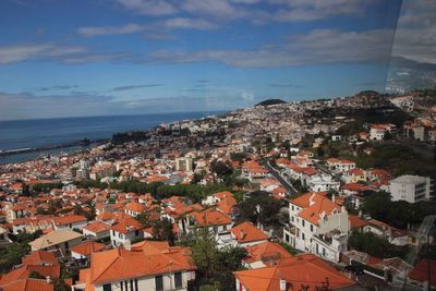 High angle view of townscape by sea against sky