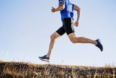 Low section of woman exercising on field against clear sky