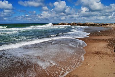 Scenic view of beach against cloudy sky