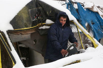A syrian refugee child sits in an old car covered in snow. syrian refugees near the turkish border.