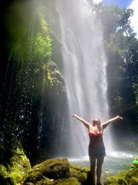 Full length of woman standing by waterfall
