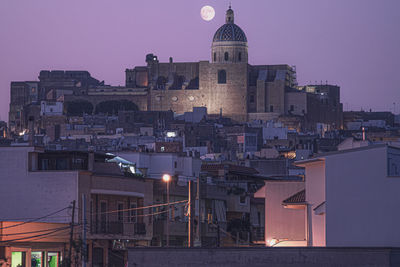 Illuminated buildings against sky at dusk