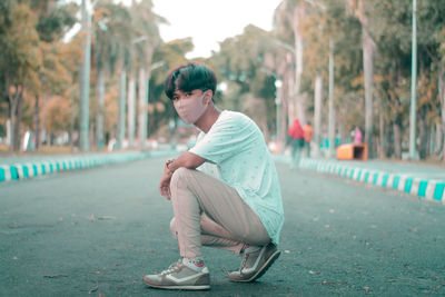 Side view of young man sitting in city