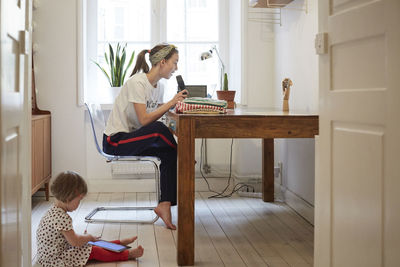 Podcaster talking on microphone while daughter using digital tablet at home