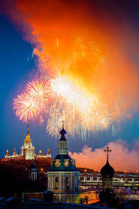 Firework display in city against sky at night