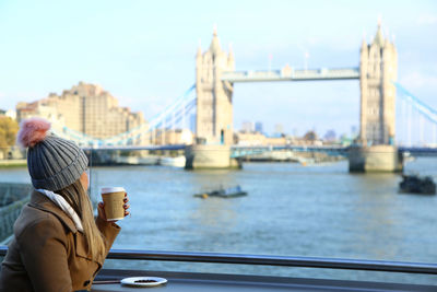 Woman looking at tower bridge against sky