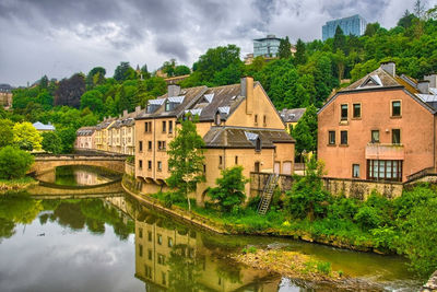 Buildings by river against sky