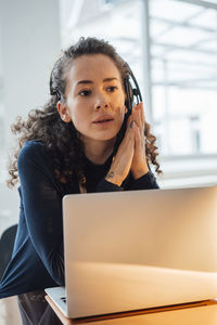 Customer service representative with laptop sitting at desk in office