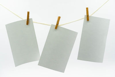 Close-up of clothespins hanging on rope against white background