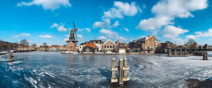 Buildings by canal against sky during winter