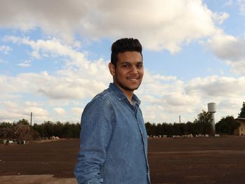 Portrait of young man standing against sky