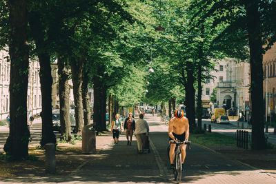 Rear view of people walking on footpath in city