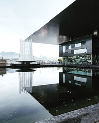 Reflection of building on river against sky in city