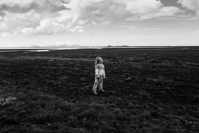 Rear view of woman standing on field against sky