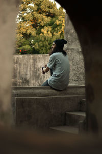 Rear view of young man sitting on retaining wall