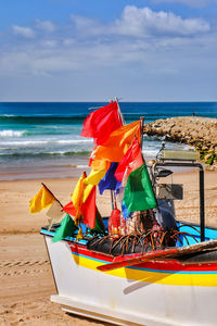 Multi colored flag on beach against sky