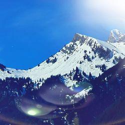 Scenic view of snowcapped mountains against blue sky
