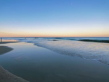 Scenic view of beach against clear sky during sunset