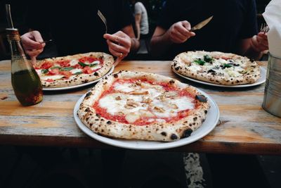 Midsection of men with pizzas