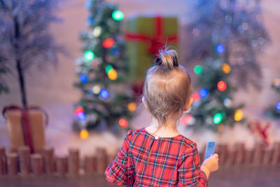 Rear view of girl standing against illuminated christmas tree