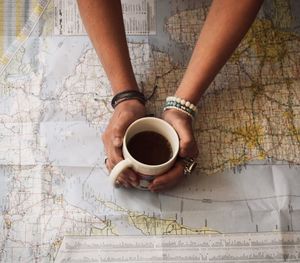 Close-up of woman holding coffee cup on table