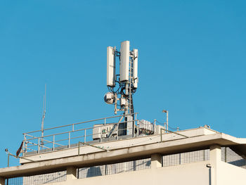 Low angle view of communications tower against clear blue sky