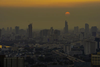 Aerial view of buildings in city at sunset