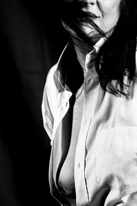 Close-up of woman with hands hair against black background