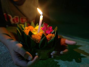 Midsection of person holding lit candles