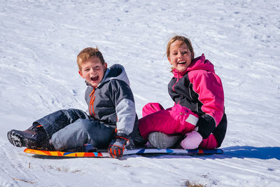 Happy friends standing on snow covered landscape during winter