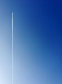 Low angle view of vapor trail against clear blue sky