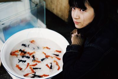 High angle portrait of young woman with fish in bowl