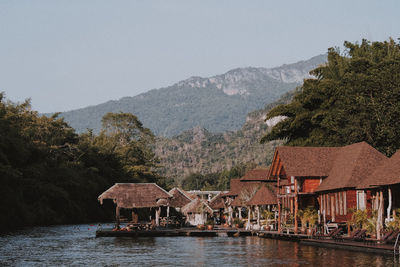 Houses by lake and buildings against sky