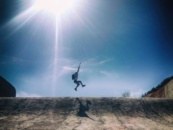 Low angle view of man jumping against sky