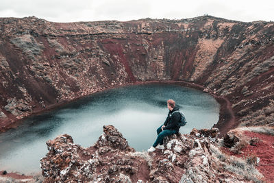 Side view of man on rock  over water