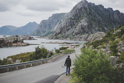 Rear view of man walking on road by river