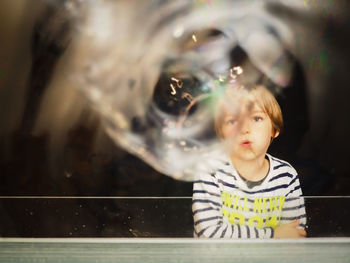 Boy playing with bubbles standing at railing