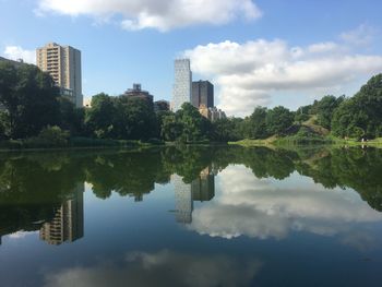 Reflection of buildings in lake against sky in city