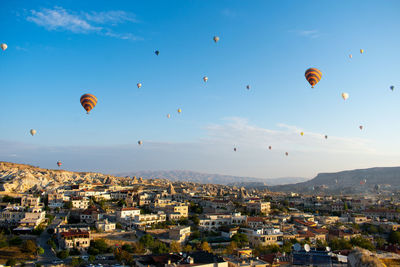 Hot air balloons flying in city against sky