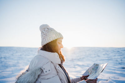 Side view of woman looking at map during winter