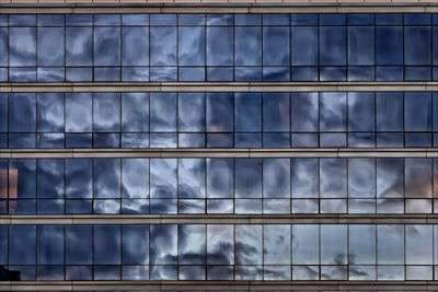 Low angle view of clouds reflected in the windows of an office building